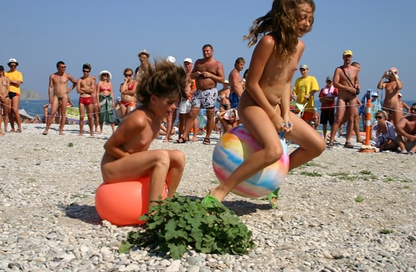 Family nudism - competition of young girls of nudists on jumps on a